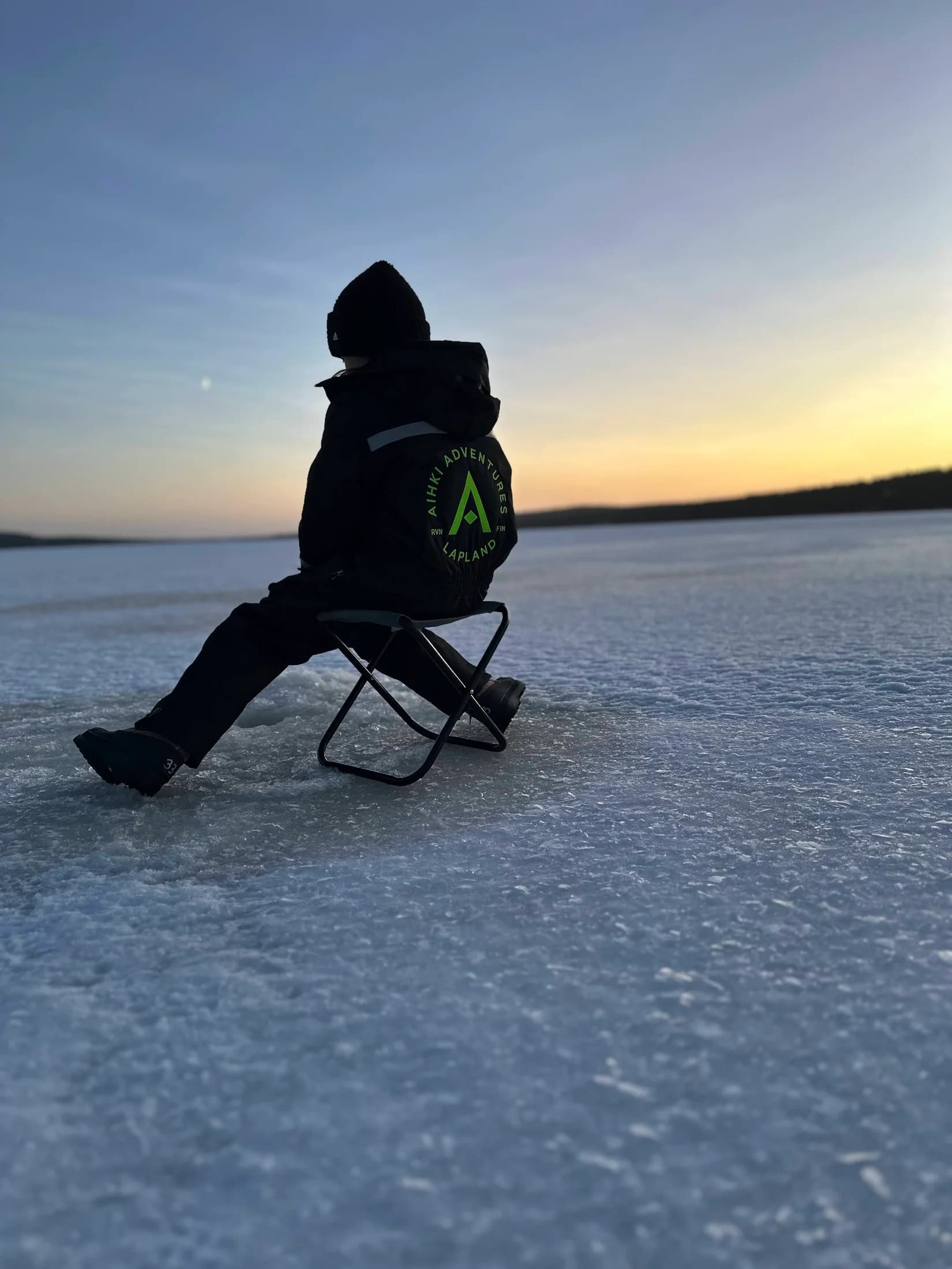 A guest sitting on a frozen lake in the soft light of sunset